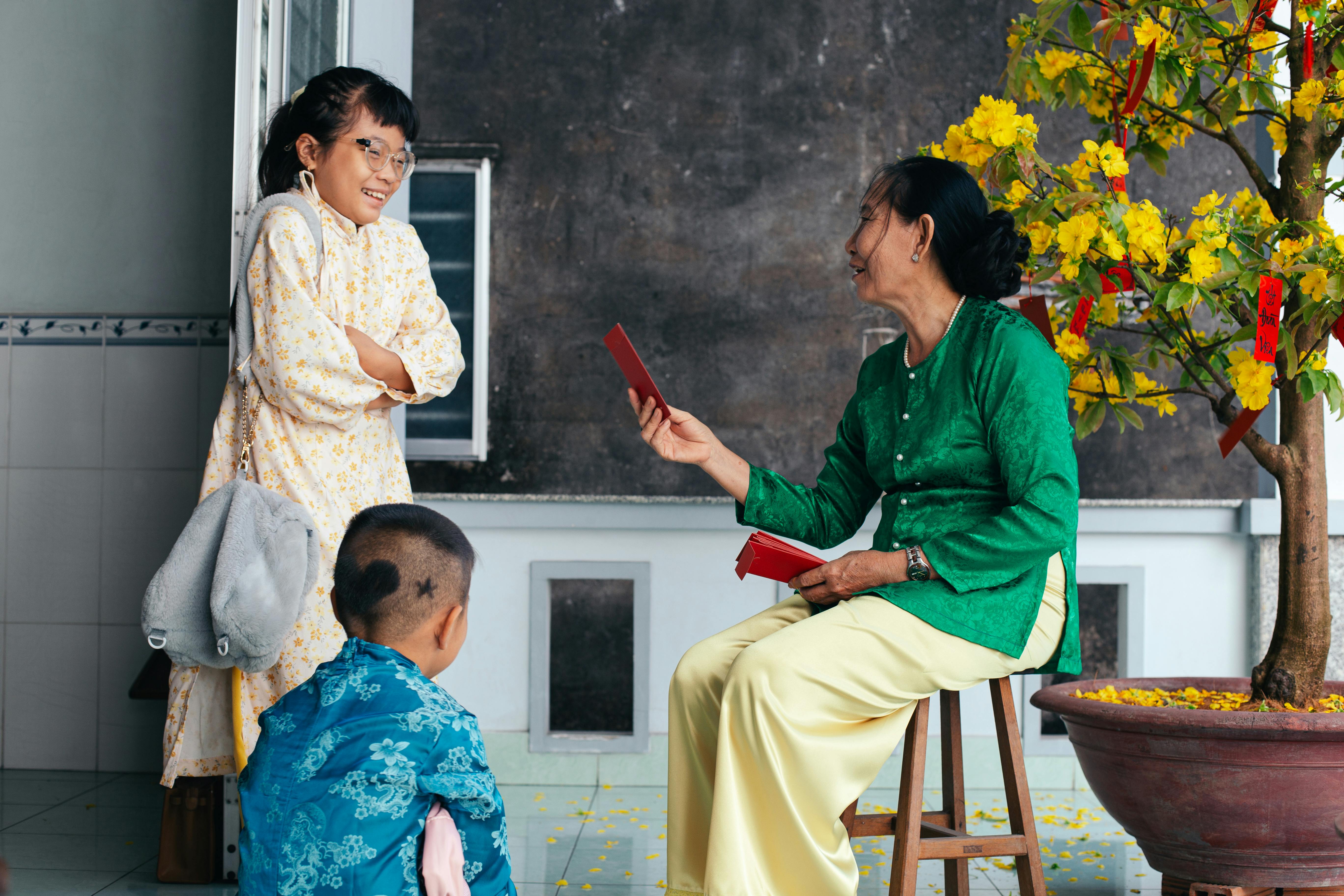 A joyful Vietnamese family exchanging red envelopes during Tet festival indoors.