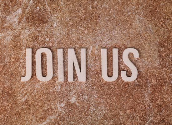 Wooden letters spelling 'Join Us' on a brown textured surface, suitable for invitations.