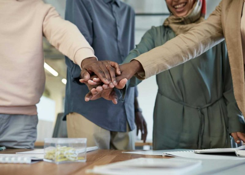 A diverse group of colleagues stacking hands, representing teamwork and unity in an office environment.